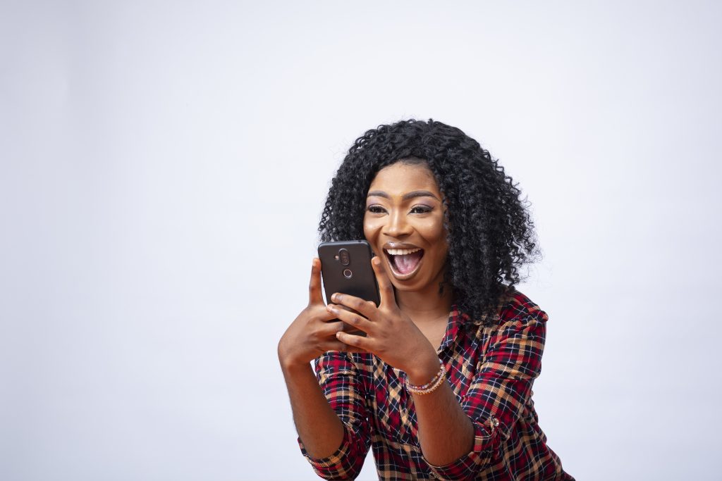 Happy Young African Female Using Her Phone Feeling Excited About Something 1024x683